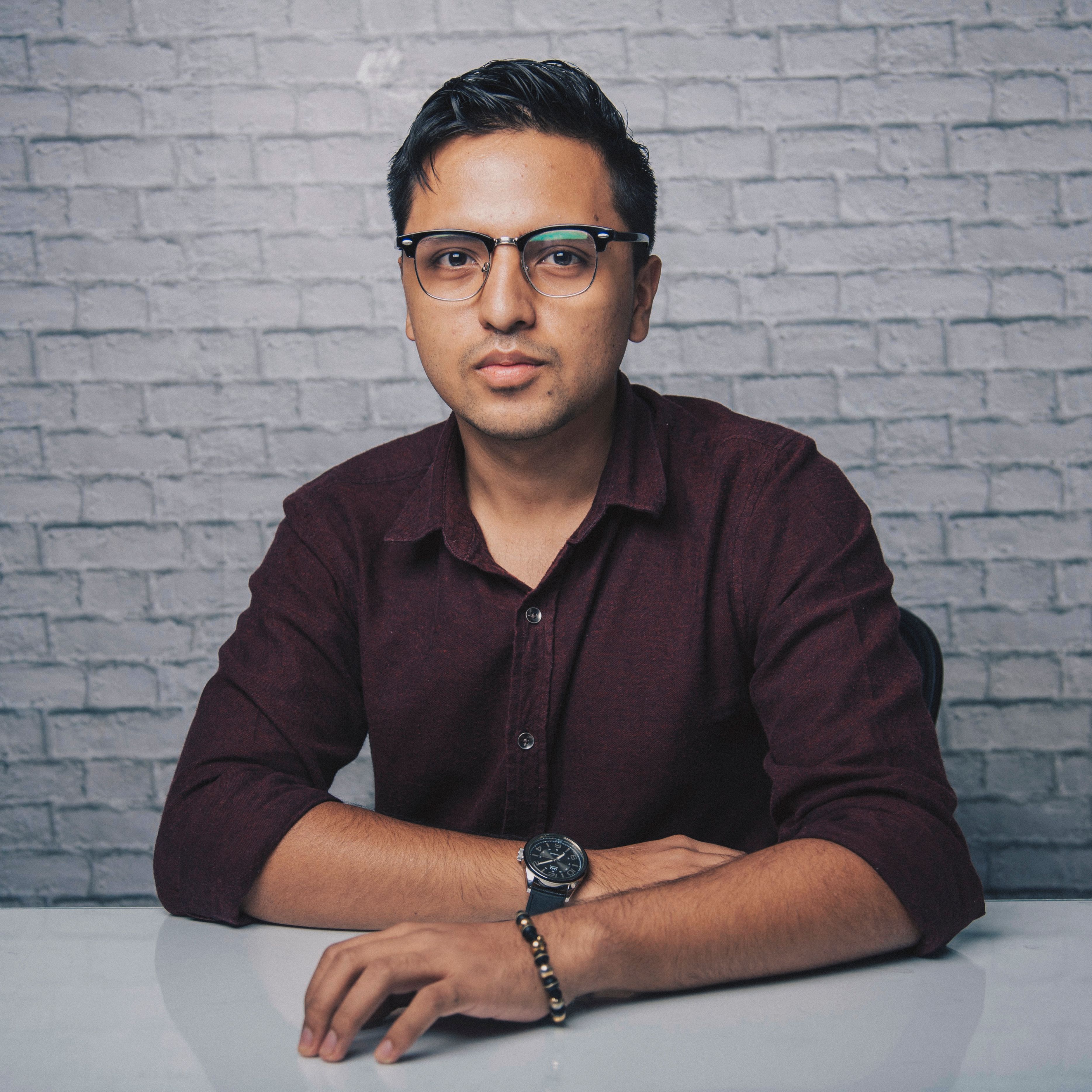 A professional portrait of a man in a gray blazer and white shirt